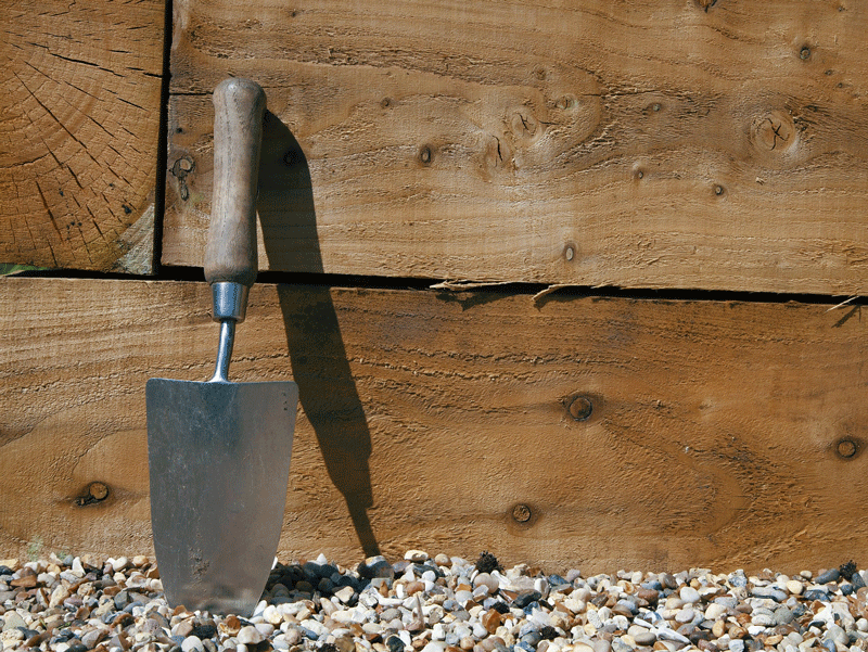 trowel leaning up against a raised garden bed 
